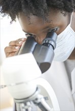 Researcher looking at specimen through microscope.