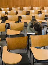 College student sleeping in empty lecture hall.