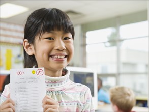 Elementary student holding an A grade paper.