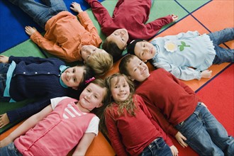 Kindergarten students lying in a circle on floor mats.