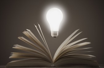 Light bulb floating above open book. Photo : Mike Kemp