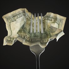 Fork pierced through American 100 dollar bill. Photo : Mike Kemp