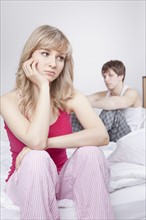 Couple sitting on bed after arguing. Photo : Take A Pix Media