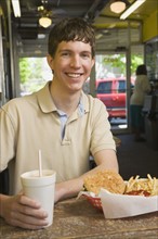 Teenage boy eating at fast food restaurant. Photo : Stewart Cohen