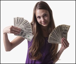 Teenage girl holding several 100 dollar bills. Photo : Mike Kemp