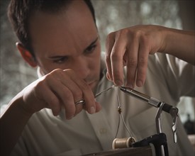 Man repairing fly fishing hook. Photo : Mike Kemp