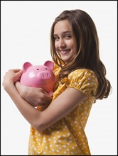 Teenage girl hugging piggy bank. Photo : Mike Kemp