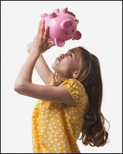 Teenage girl trying to get money out of piggy bank. Photo : Mike Kemp