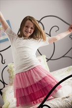 Young girl dancing on her bed. Photo : Mike Kemp