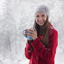Woman in the snow holding a warm drink. Photo : Mike Kemp