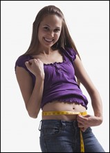 Teenage girl measuring her waist. Photo : Mike Kemp