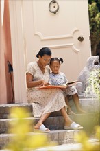 Mother and daughter reading together on front steps. Photo : Rob Lewine