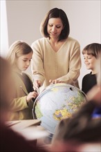 Elementary school teacher showing globe to students. Photo : Rob Lewine