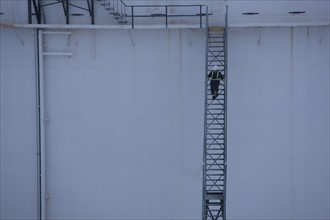 Worker walking down stairs on an oil tank. Photo : Dan Bannister