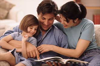 Parents and their young daughter reading together. Photo : Rob Lewine