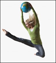Woman jumping in air while holding globe. Photo : Mike Kemp