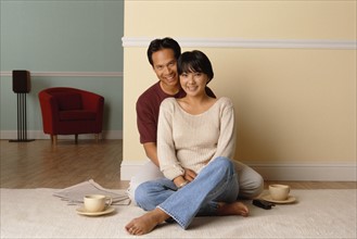 Happy couple sitting together on the floor in their home. Photo : Rob Lewine