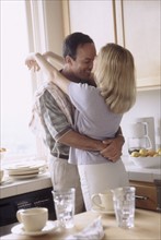 Couple embracing in their kitchen. Photo : Rob Lewine