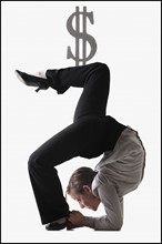 Dollar symbol on top of contorted businesswoman. Photo : Mike Kemp