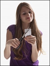 Woman cutting up a credit card. Photo : Mike Kemp