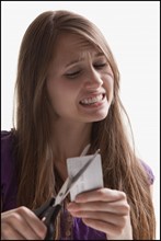 Woman reluctantly cutting her credit card. Photo : Mike Kemp