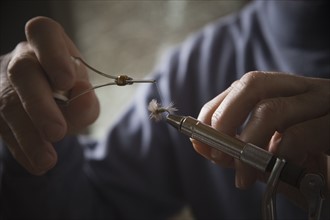 Hands working on fly fishing hook. Photo : Mike Kemp