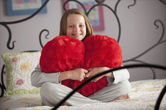Young girl holding a heart pillow. Photo : Mike Kemp