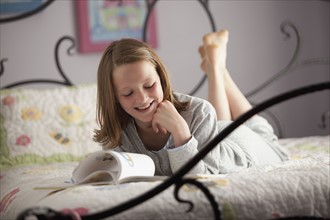 Young girl reading on her bed. Photo : Mike Kemp