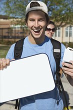 Happy teenage student holding blank whiteboard. Photo : Stewart Cohen