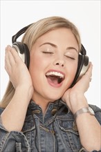 Pretty blond woman singing while wearing headphones. Photo : K.Hatt