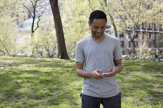Man in casual clothing texting in park. Photo : David Engelhardt