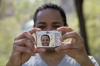 Man taking self portrait with digital camera. Photo : David Engelhardt