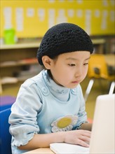 Kindergarten student working on laptop in classroom.