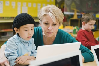Teacher and kindergarten student looking at laptop.