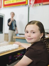 Elementary student sitting at desk in classroom.