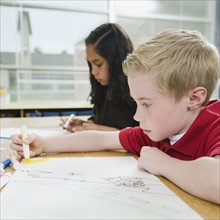 Elementary students drawing at their desks.