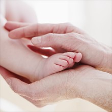 Hands cradling baby's foot. Photo : Jamie Grill