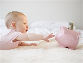 Baby reaching for piggy bank. Photo. Jamie Grill