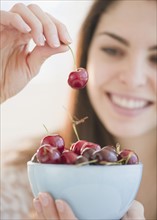 Young woman holding a bowl of cherries. Photo : Jamie Grill