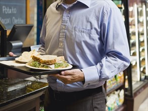 Man carrying sandwich on tray.