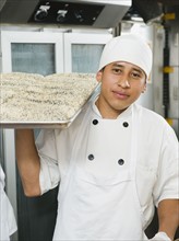 Chef holding tray of bread.