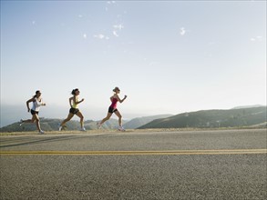 Runners training on side of a road.