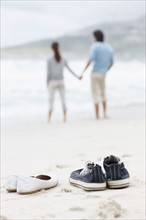 Couple walking barefoot at the beach. Photo. momentimages