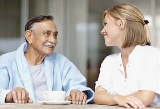 Nurse and senior patient sitting at table. Photo : momentimages
