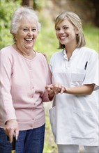 Nurse assisting senior walking with a cane. Photo. momentimages