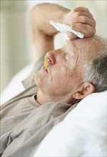Senior man with a thermometer in his mouth. Photo. momentimages