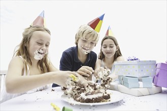 Children eating birthday cake with their hands. Photo : momentimages