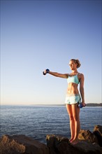 Athletic woman lifting weights outdoors. Photo : Take A Pix Media
