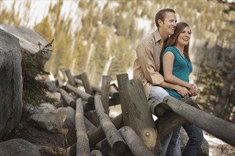 Happy couple sitting on log fence. Photo. FBP