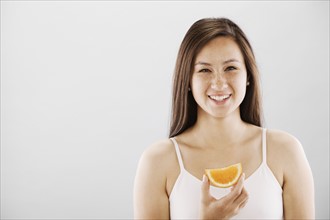 Woman holding a slice of orange. Photo. FBP